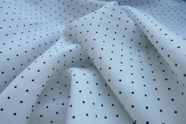 Textur aus Seidenstoff Schwarze Tupfen auf weißem Hintergrund Kleid aus leichtem Synthetikstoff in Weiß mit sich wiederholendem Muster Das Textil besteht aus Wellen und Falten Femininer klassischer Stil