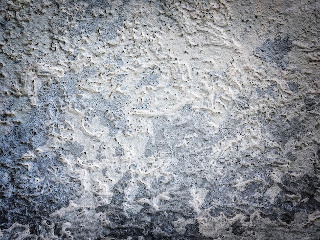 Textur der alten Wand mit dekorativem Putz in weißer und blauer Farbe. Gefleckter Beton verwitterte Grunge-Hintergrund mit Vignette. Abstrakte Steinstuckoberfläche, Nahaufnahme.