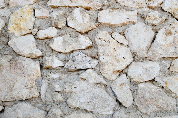 Textur der gelben, alten, baufälligen Wand mit scharf geschnitzten Natursteinen