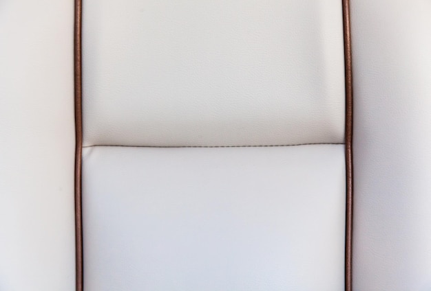 Textur eines weißen Lederstuhls, Polsterung mit braunen Akzenten, Nahaufnahme, weißer Ledergrund