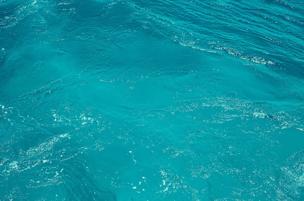 Textur Hellblaue Oberfläche aus tobendem Meerwasser mit weißem Schaum und Wellenmuster
