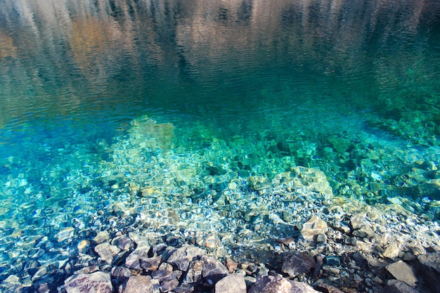 Textur von smaragdgrünem klarem Wasser und Natursteinen Natürlicher Hintergrund Blauer See