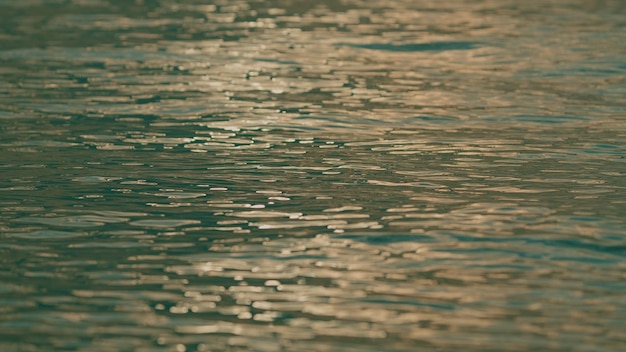 Textur Wasseroberfläche kleine Wellen Wellen beim Sonnenuntergang im Sommerabend Wasser ätzender Hintergrund