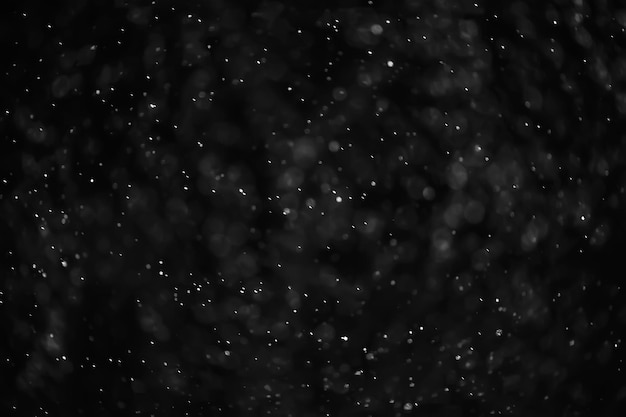 textura abstracta de fondo negro de nieve, copos de nieve cayendo en el cielo superpuesto