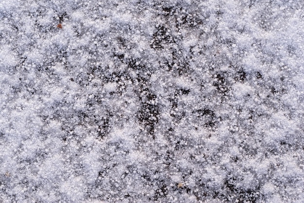 Textura abstracta de nieve y copos de nieve sobre el asfalto congelado con hielo para un fondo natural