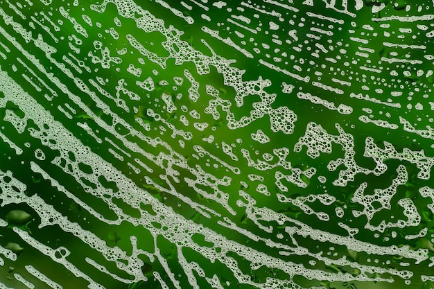 Textura abstracta verde brillante con patrón de espuma de jabón en vidrio