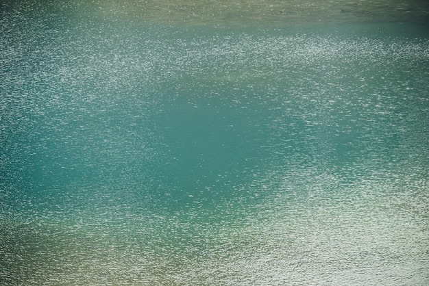 Textura de aguas tranquilas azul verdoso del lago. Ondas meditativas en la superficie del agua. Fondo mínimo de naturaleza de lago azul verde con brillo dorado. Telón de fondo natural del fragmento del lago con agua azul clara.