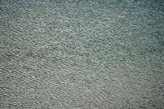 Textura de aguas tranquilas de color verde oscuro del lago. Ondas meditativas en la superficie del agua. Fondo mínimo de la naturaleza del lago verde profundo. Telón de fondo natural de agua turquesa oscura clara. Fotograma completo del fragmento del lago