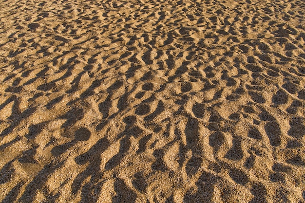 Textura de arena Superficie irregular. Sombras duras al mediodía en la arena.