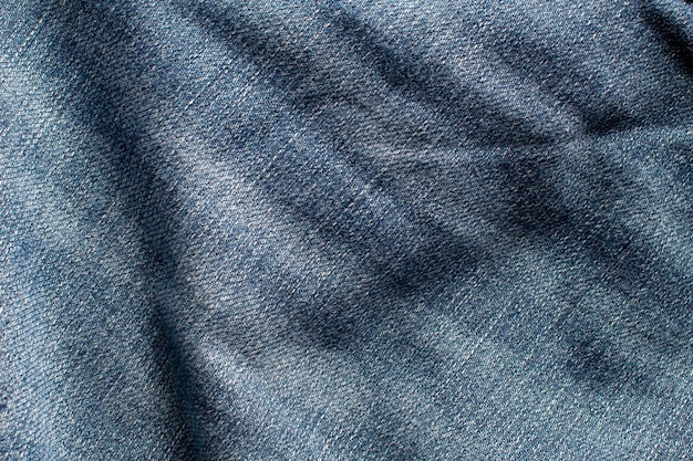 La textura de un blue jeans con ondas y formando sombras.