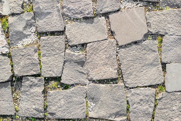 Textura de carreteras de mampostería hechas de piedras asimétricas con hierba entre la mampostría Vista superior