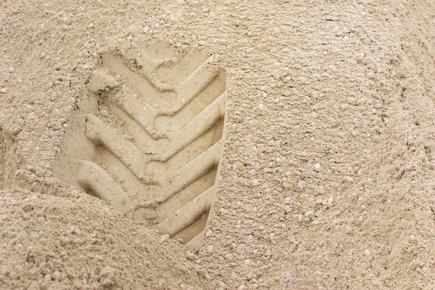 Textura de areia com grãos visíveis e impressão da roda na superfície. Foto com espaço em branco de cópia.