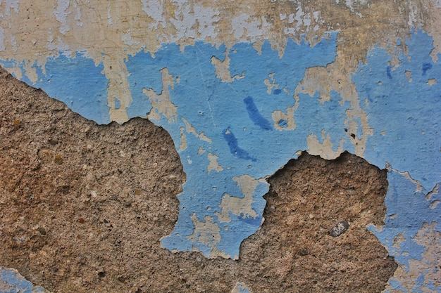 Textura de cimento no fundo da parede rachada com tinta azul descascada