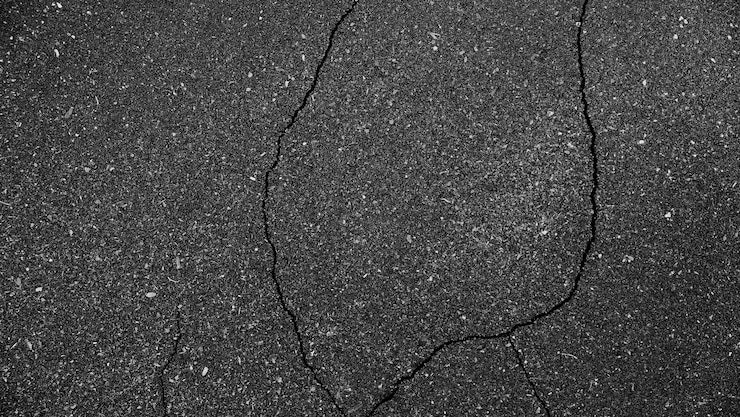 Foto textura de estrada rachada e velha de cor preta