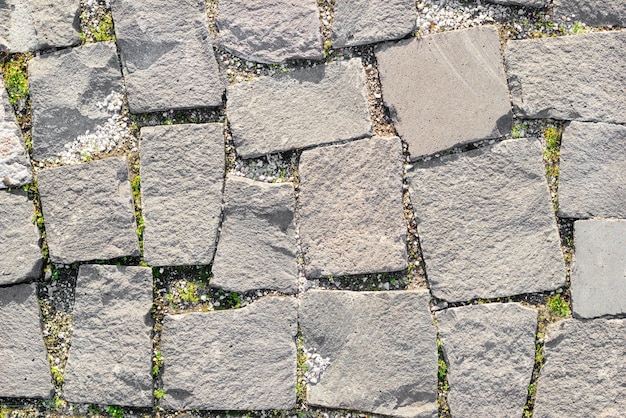 Textura de estradas de alvenaria feitas de pedras assimétricas com grama entre a alvenaria Vista superior