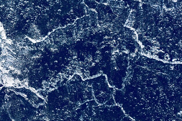 Textura de gelo com bolhas congeladas e rachaduras em um fundo azul escuro. fundo decorativo abstrato bonito. design abstrato elegante para envoltórios, presentes, tecidos, têxteis, mobiliário. padrão de inverno.