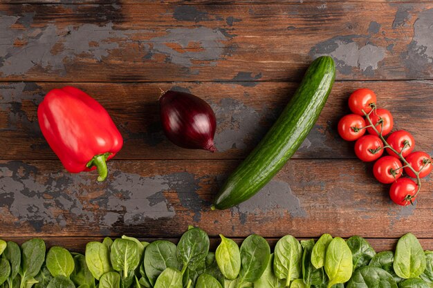 Textura de madeira com legumes pimenta vermelha tomate cereja pepino espinafre cebola vermelha vista superior