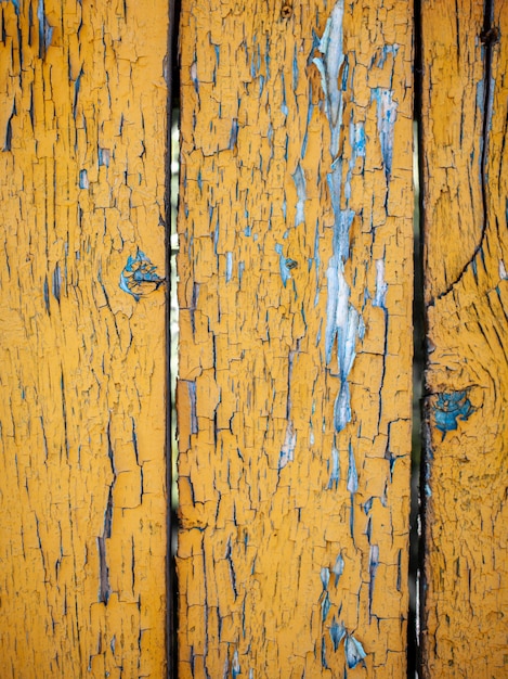 Textura de madeira com tinta amarela em flocos. Pintura descascada em madeira envelhecida. Antigo padrão de pintura rachada em fundo enferrujado. Tinta rachada em uma superfície de madeira velha