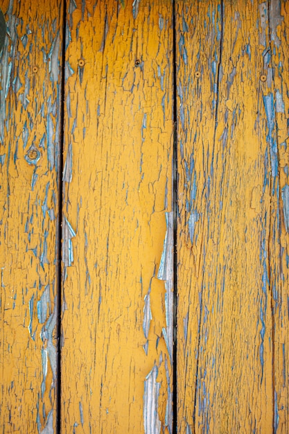 Textura de madeira com tinta amarela em flocos. Pintura descascada em madeira envelhecida. Antigo padrão de pintura rachada em fundo enferrujado. Tinta rachada em uma superfície de madeira velha