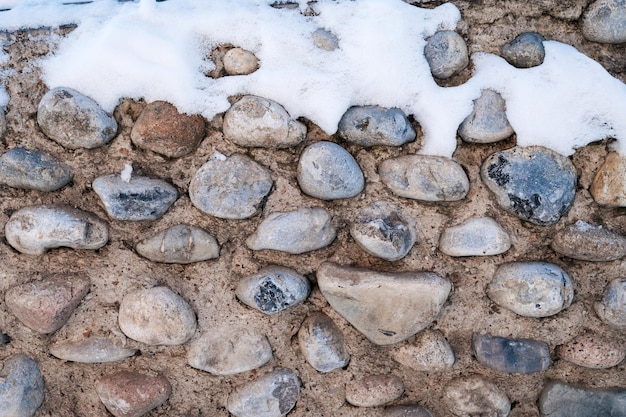 Textura de pedras de paralelepípedos na velha parede de concreto no inverno com neve