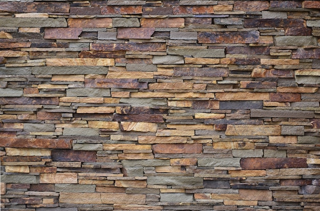 Textura de um muro de pedra de pedras longas e difíceis de diferentes tamanhos e tons