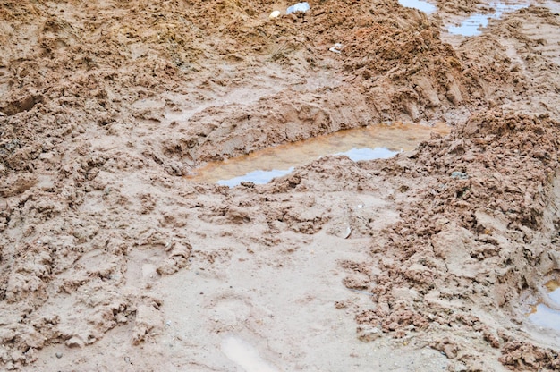 Foto textura de uma estrada de terra suja e ruim estrada de terra com poças e lama de secagem de argila com rachaduras e sulcos