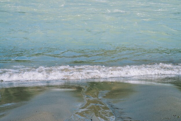 Textura detallada de turquesa corriendo superficie del agua y la arena. Rápidos del río de la montaña de cerca. Fondo de ondas de agua limpia en la playa.