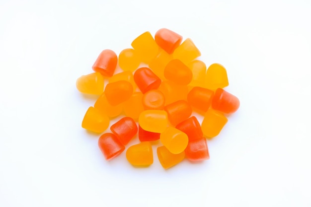 Textura do close up de gomas multivitamínicas laranjas e amarelas em forma de ursos em fundo branco