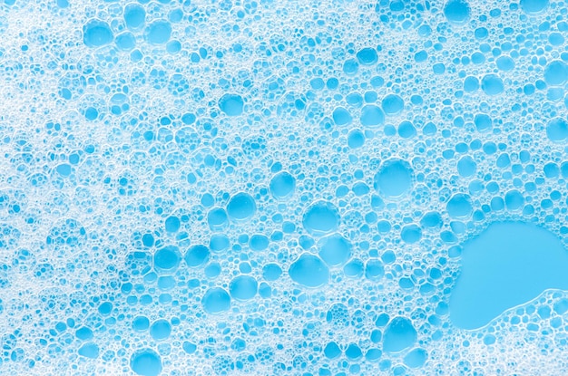 Textura de espuma blanca sobre fondo azul Mousse limpiadora para la cara o espuma de baño o detergente en polvo Primer plano