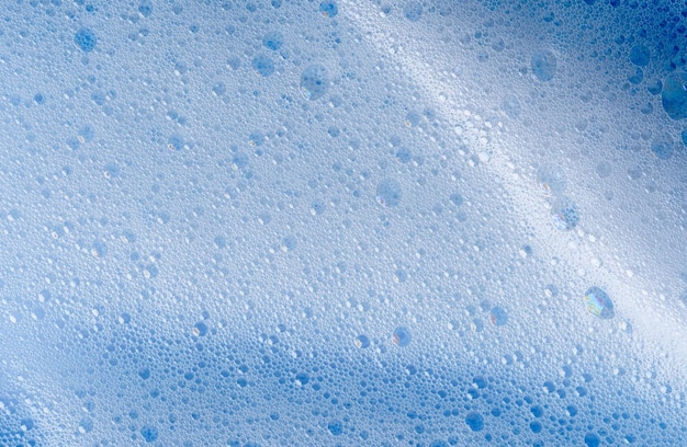 Textura de espuma blanca sobre fondo azul Producto cosmético de espuma para el procedimiento de cuidado de la piel