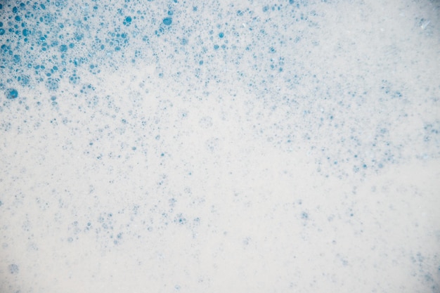 Textura de fondo abstracto de espuma de jabón blanco. Espuma de champú con burbujas sobre un fondo azul. Detergentes e higiene.