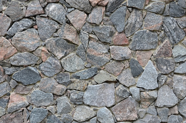 La textura de un fuerte muro de piedra de muchas piedras de varias formas de hormigón.