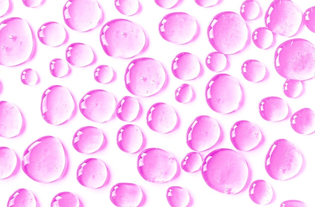 La textura de un gel líquido transparente para la limpieza facial Muestra de suero de aceite con burbujas sobre un fondo rosa Producto cosmético hidratante para el cuidado de la piel Loción para piel seca Concepto de belleza