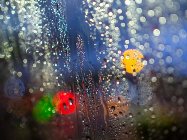 Textura de gotas de lluvia borrosa en la ventana del coche con fondo abstracto colorido bokeh