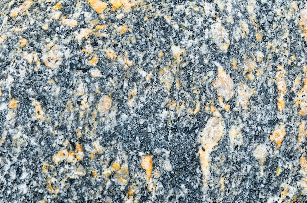 Foto textura de granito natural, negro con impregnación amarillo-naranja.