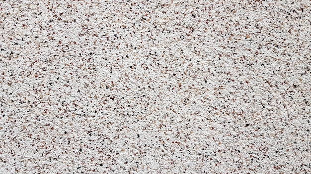 Foto textura granulada da superfície da fachada do edifício. gesso granulado. detalhes do fundo da textura do arenito. vista superior da praia de areia. fundo com espaço de cópia e textura de areia visível.