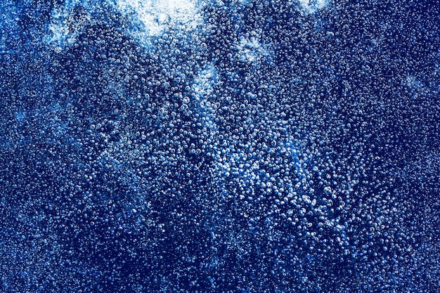 Foto textura de hielo con burbujas congeladas y grietas sobre un fondo azul oscuro. hermoso fondo decorativo abstracto. elegante diseño abstracto para envolturas, regalos, telas, textiles, mobiliario. patrón de invierno.