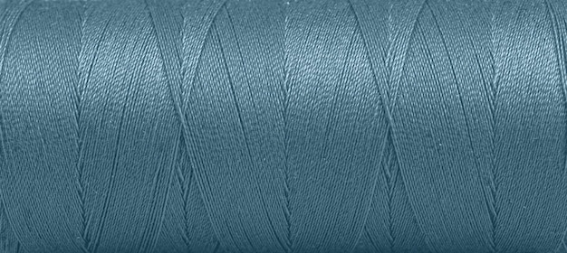 Textura de los hilos en un carrete de color azul en un primer plano de fondo blanco