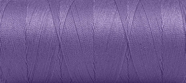 Textura de los hilos en un carrete de color púrpura en un fondo blanco de primer plano