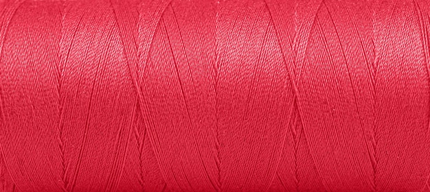 Textura de hilos en un carrete de color rojo sobre un fondo blanco.