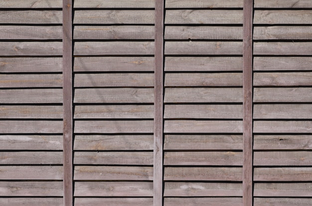 Textura horizontal de una pared de varias filas de viejos tableros de madera marrones. Pared de madera pintada en color marrón.