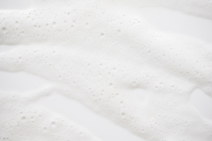 Textura jabonosa blanca abstracta de la espuma. Champú de espuma con burbujas.