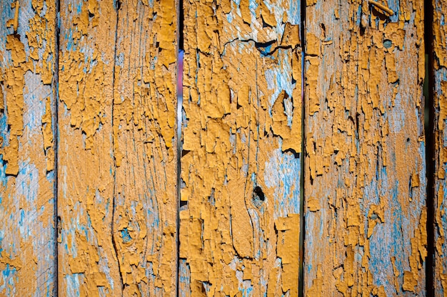 Textura de madera con pintura amarilla en escamas. Pintura descascarada sobre madera desgastada. Viejo patrón de pintura agrietada sobre fondo oxidado. Pintura agrietada sobre una superficie de madera vieja