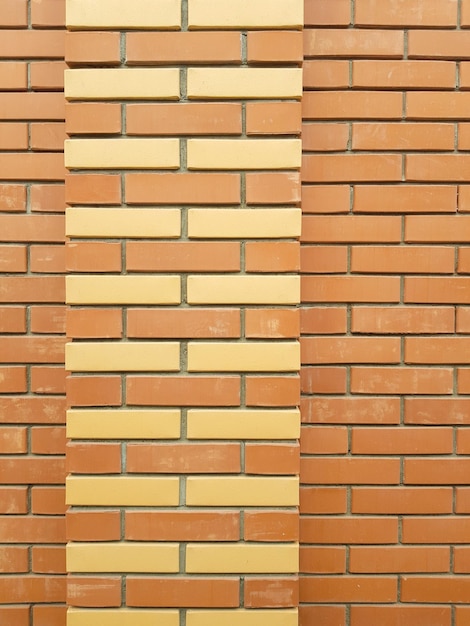 La textura moderna de una pared de ladrillo naranja con un adorno de ladrillo amarillo es el material de fondo de la construcción industrial