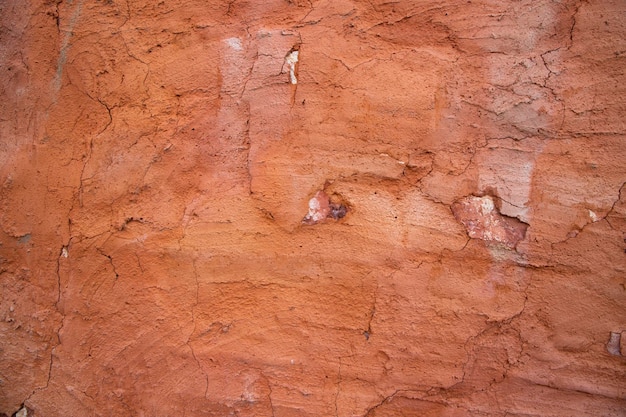 La textura de un muro de hormigón rojo con grietas y arañazos se puede utilizar como fondo
