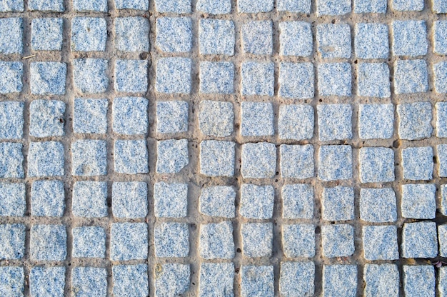 Textura de un muro de piedra caminos de piedras ladrillos adoquines azulejos con costuras arenosas de gris