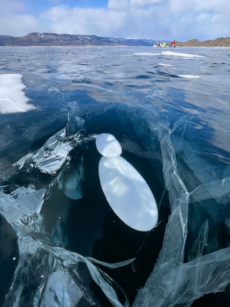 La textura natural del hielo invernal con burbujas blancas y grietas en un lago congelado Fondo abstracto de hielo y grietas en la superficie del lago Baikal congelado