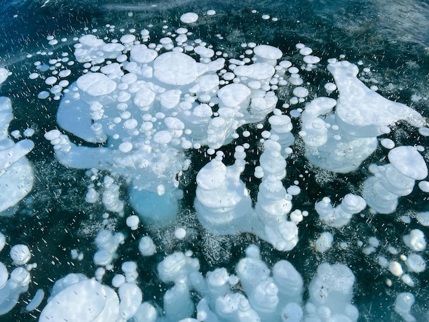 La textura natural del hielo invernal con burbujas blancas y grietas en un lago congelado Fondo abstracto de hielo y grietas en la superficie del lago Baikal congelado