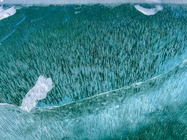 La textura natural del hielo invernal con burbujas blancas y grietas en un lago congelado Fondo abstracto de hielo y grietas en la superficie del lago Baikal congelado