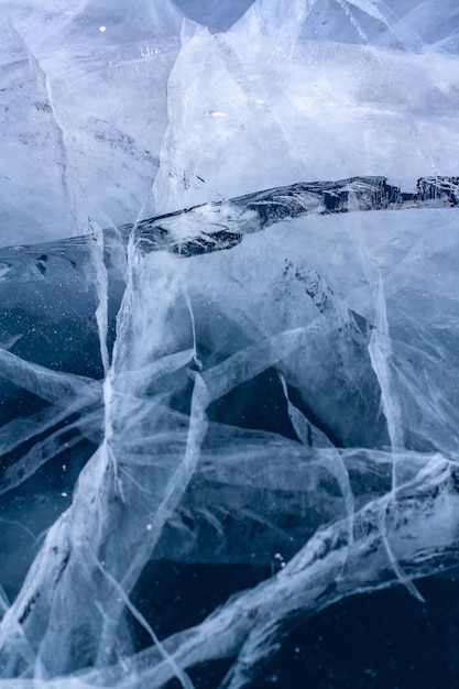 Textura natural de un lago de invierno con grietas en hielo transparente transparente Hielo grueso azul Vertical
